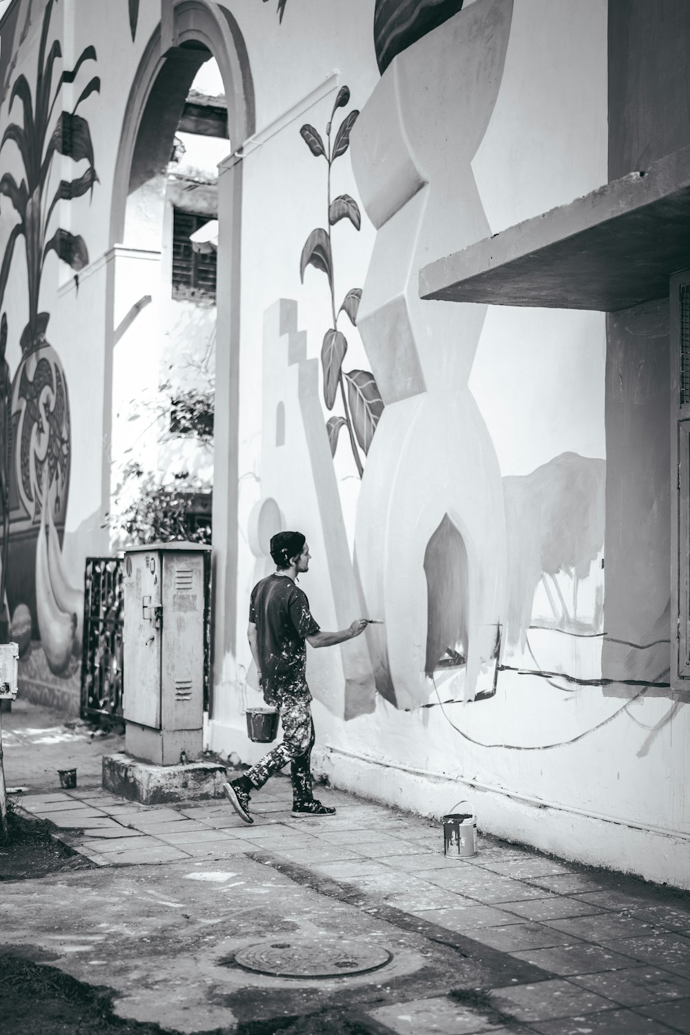 greyscale photo of man painting on wall