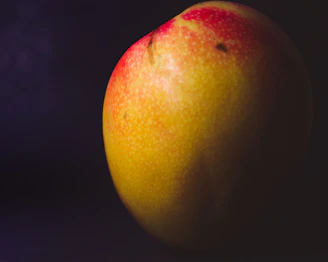 Close-up of ripe Chunsa mangoes with golden-yellow skin glistening in sunlight.