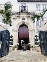 A wide shot of a grand entrance showcasing a charcoal gray iron door with intricate lattice design.
