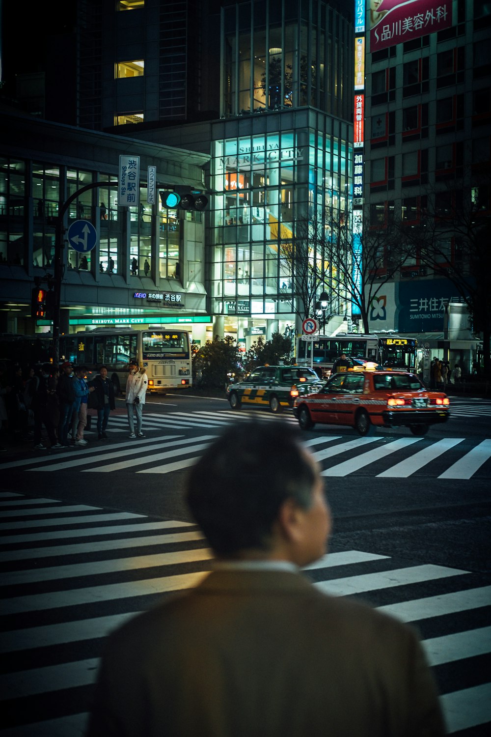 hombre parado cerca de la carretera al lado de los edificios durante la noche