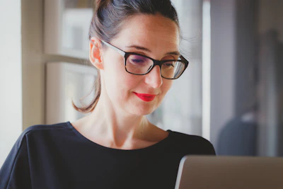 Professional businesswoman reviewing software licenses on a laptop with a red accent background.