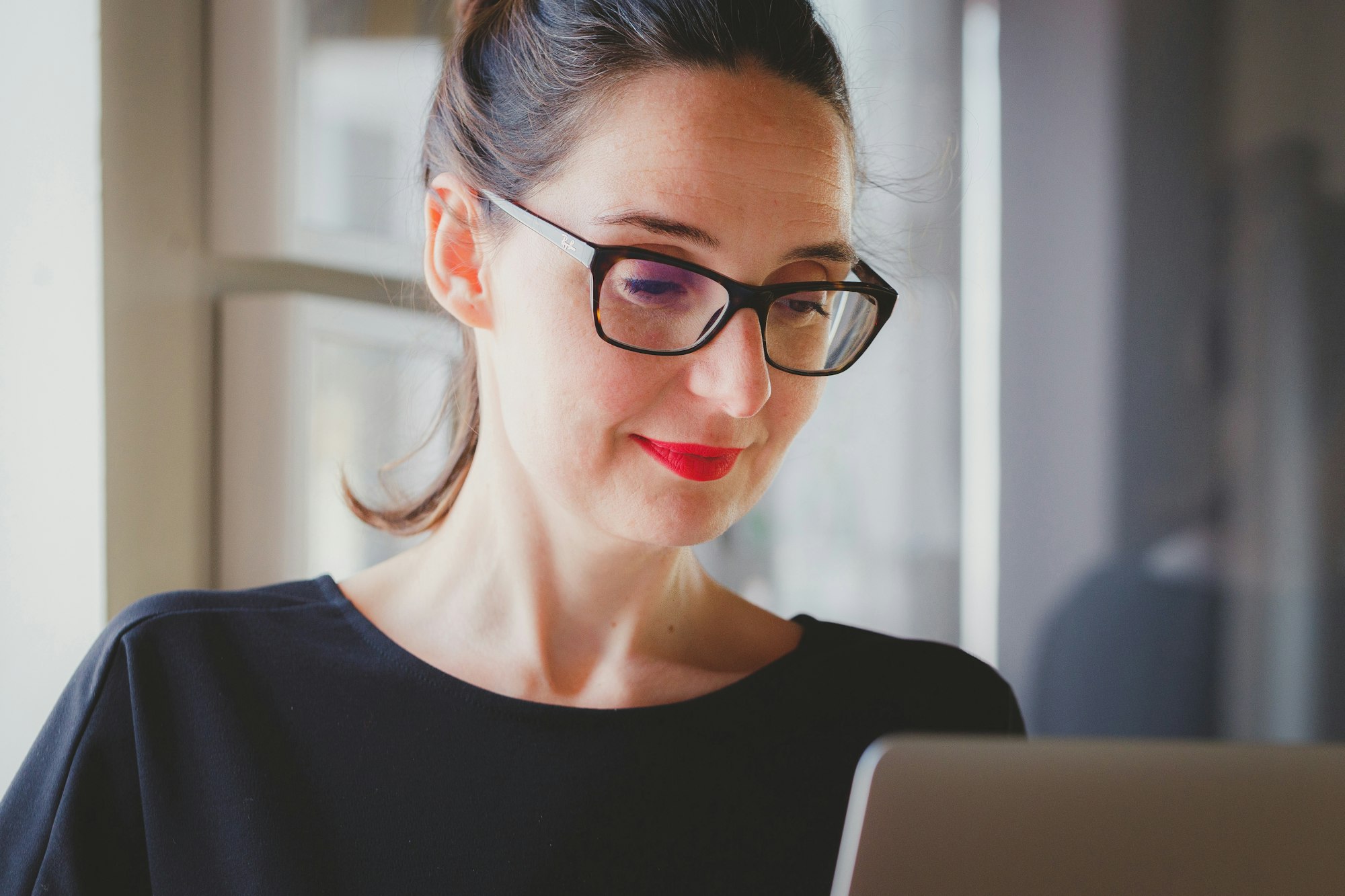 Donna con occhiali che lavora dal computer come tradruttrice online