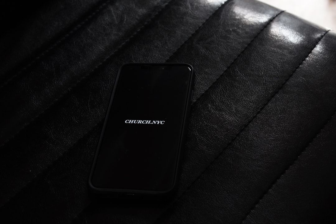 turned-on black smartphone on black leather sofa
