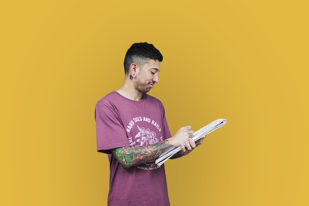 man wearing red crew-neck t-shirt holding white printer paper