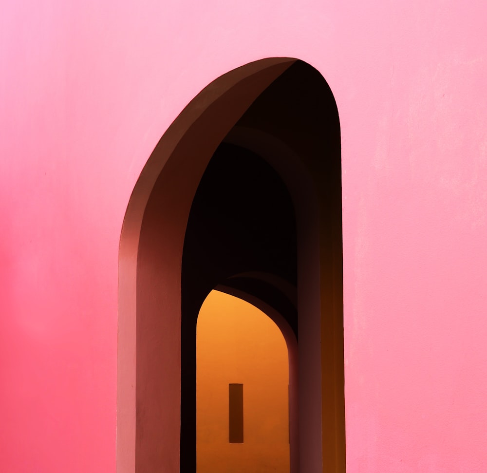 a pink wall with a doorway and a light at the end