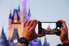 person taking photo a castle using smartphone