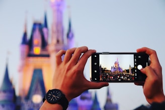 person taking photo a castle using smartphone