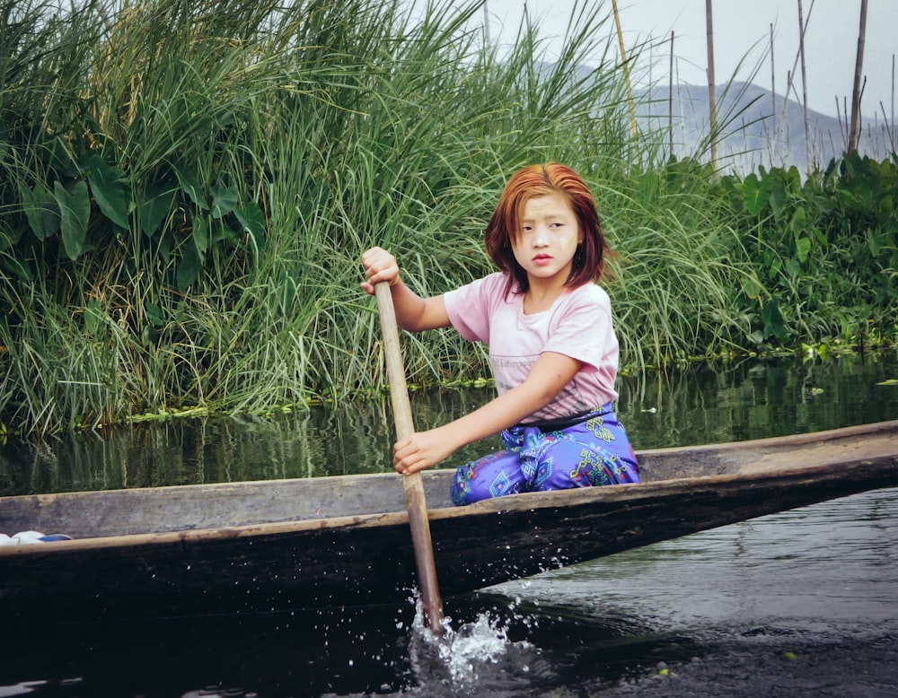 woman riding on black row boat