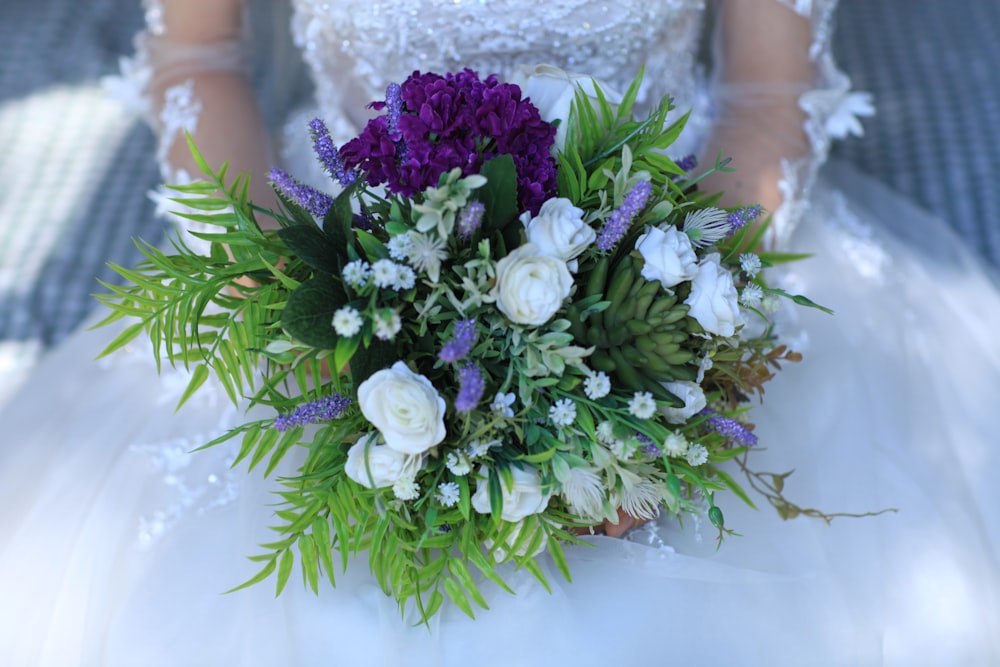 Mujer sosteniendo ramo de flores blancas y púrpuras