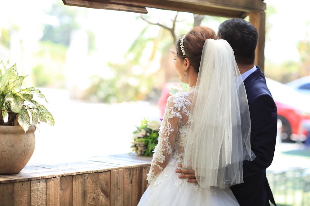 wedded couple standing beside window