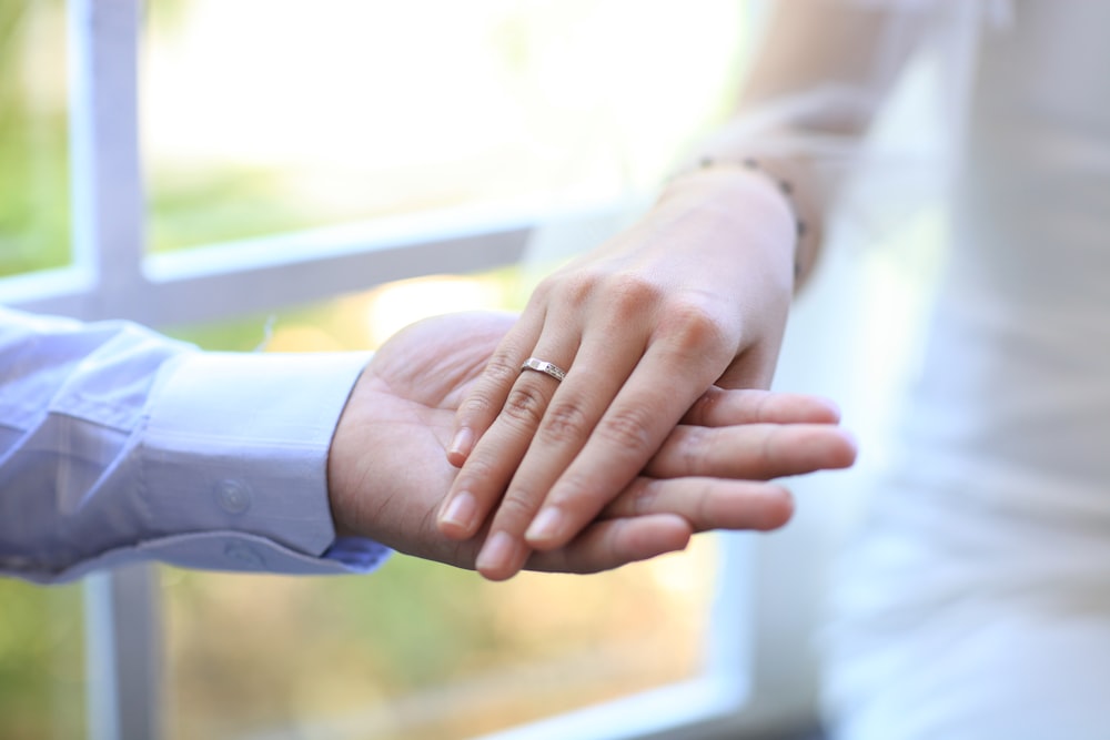 selective focus photography of man holding women's right hand with ring