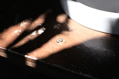 Close-up of wedding rings on a rustic wooden table with soft natural light.