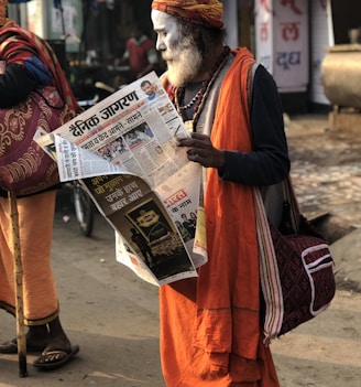 man reading newspaper beside street