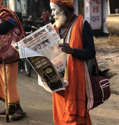 man reading newspaper beside street