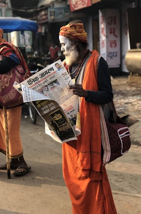 man reading newspaper beside street