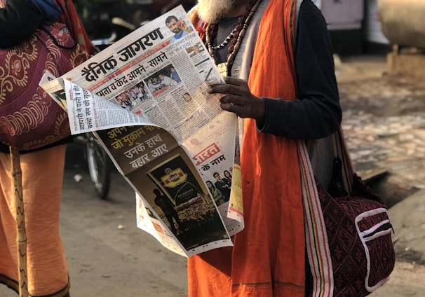 man reading newspaper beside street