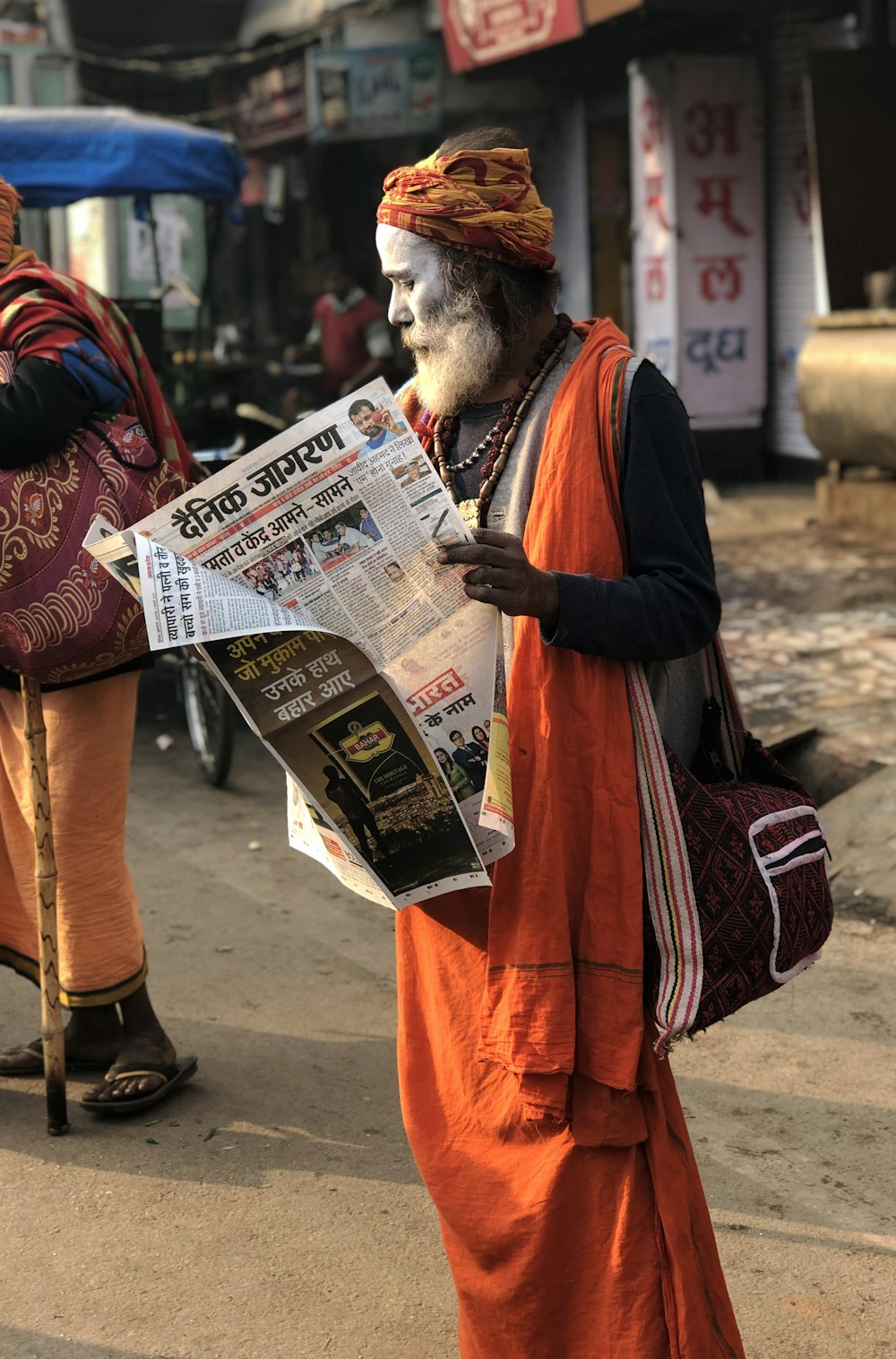 man reading newspaper beside street