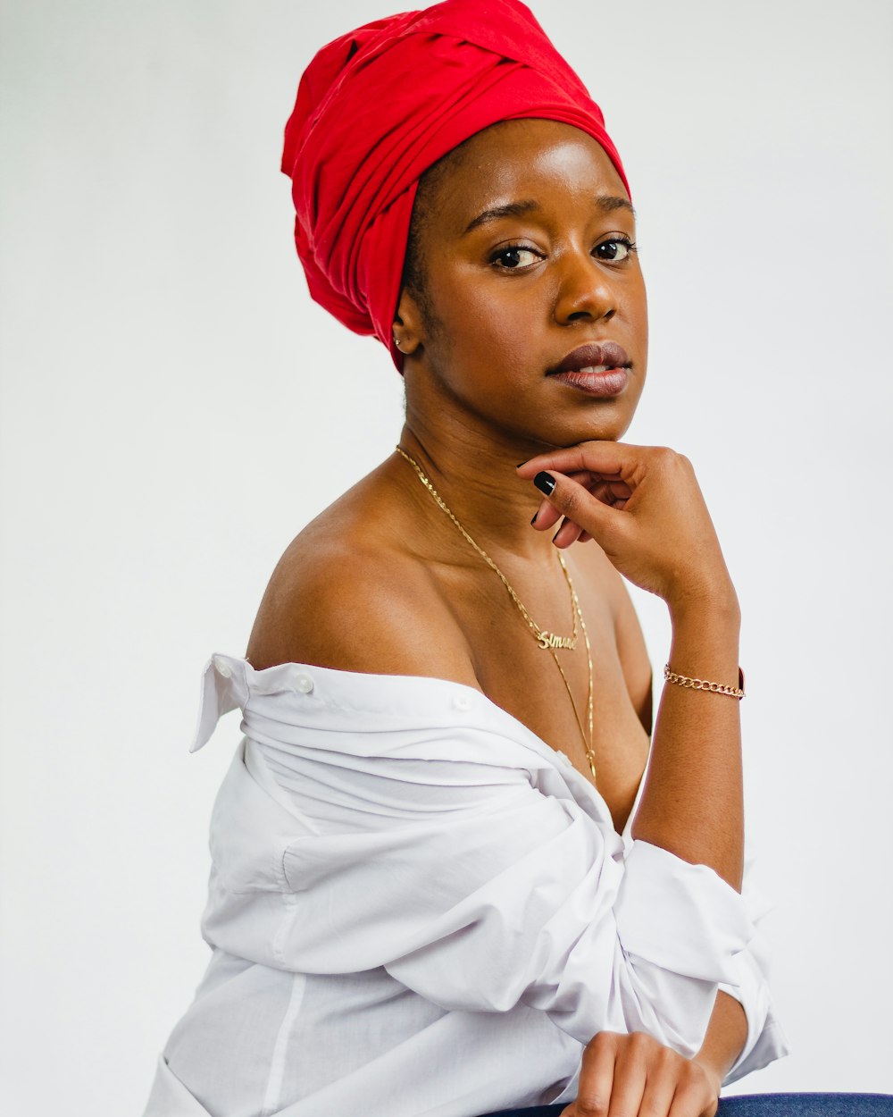 woman in white top with right hand on chin