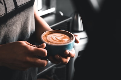 A vibrant coffee cup with latte art held by a smiling attendee at a social gathering.
