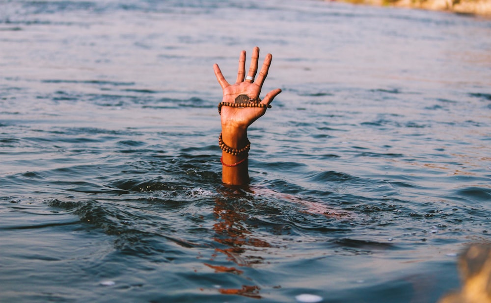 person underwater raising right hand