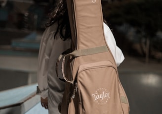 woman carrying brown Taylor guitar bag outdoor