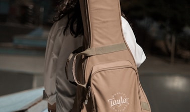 woman carrying brown Taylor guitar bag outdoor