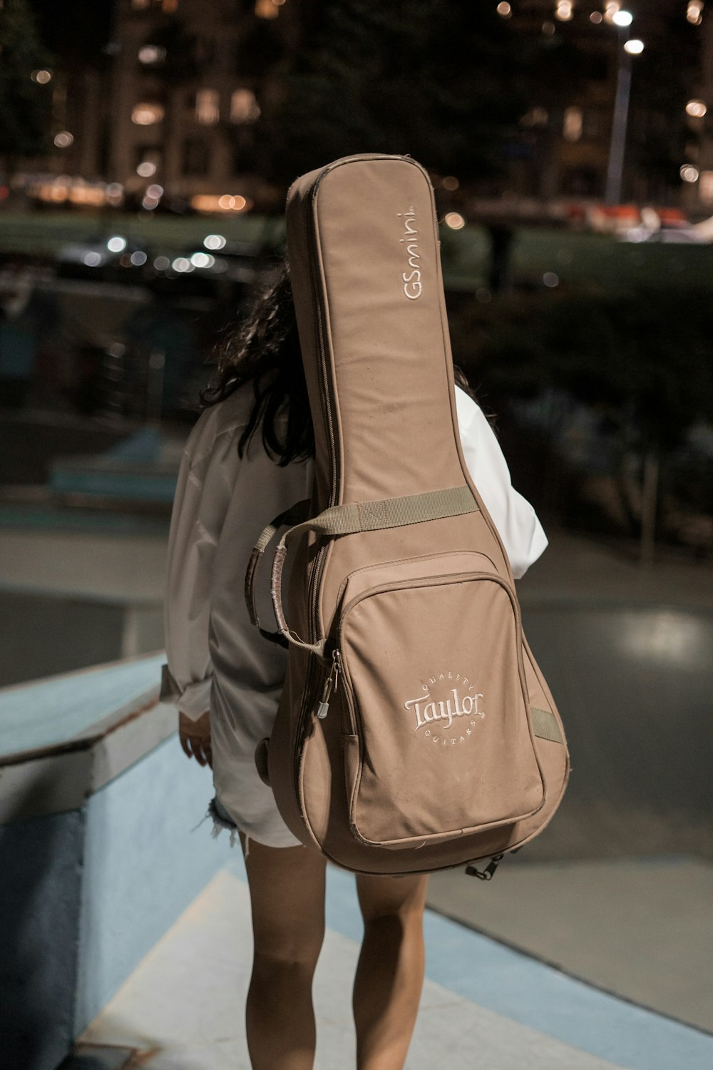 woman carrying brown Taylor guitar bag outdoor