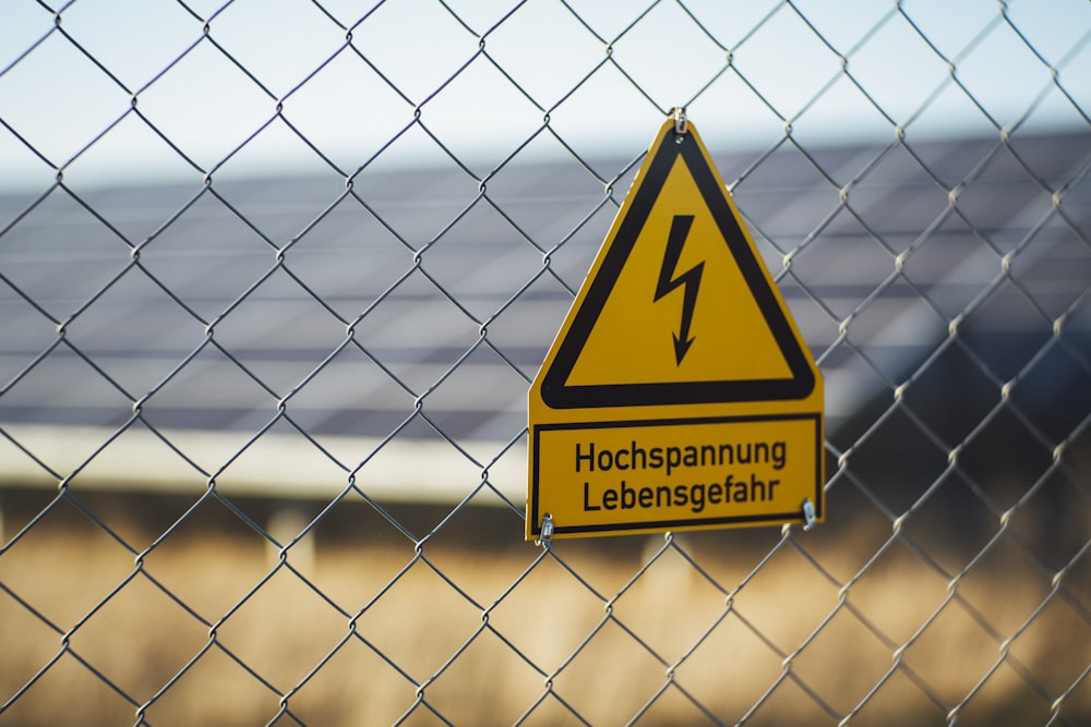 selective focus photography of danger high voltage signage on chain-link fence