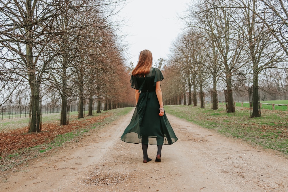 Mujer con vestido verde caminando por el camino de arena