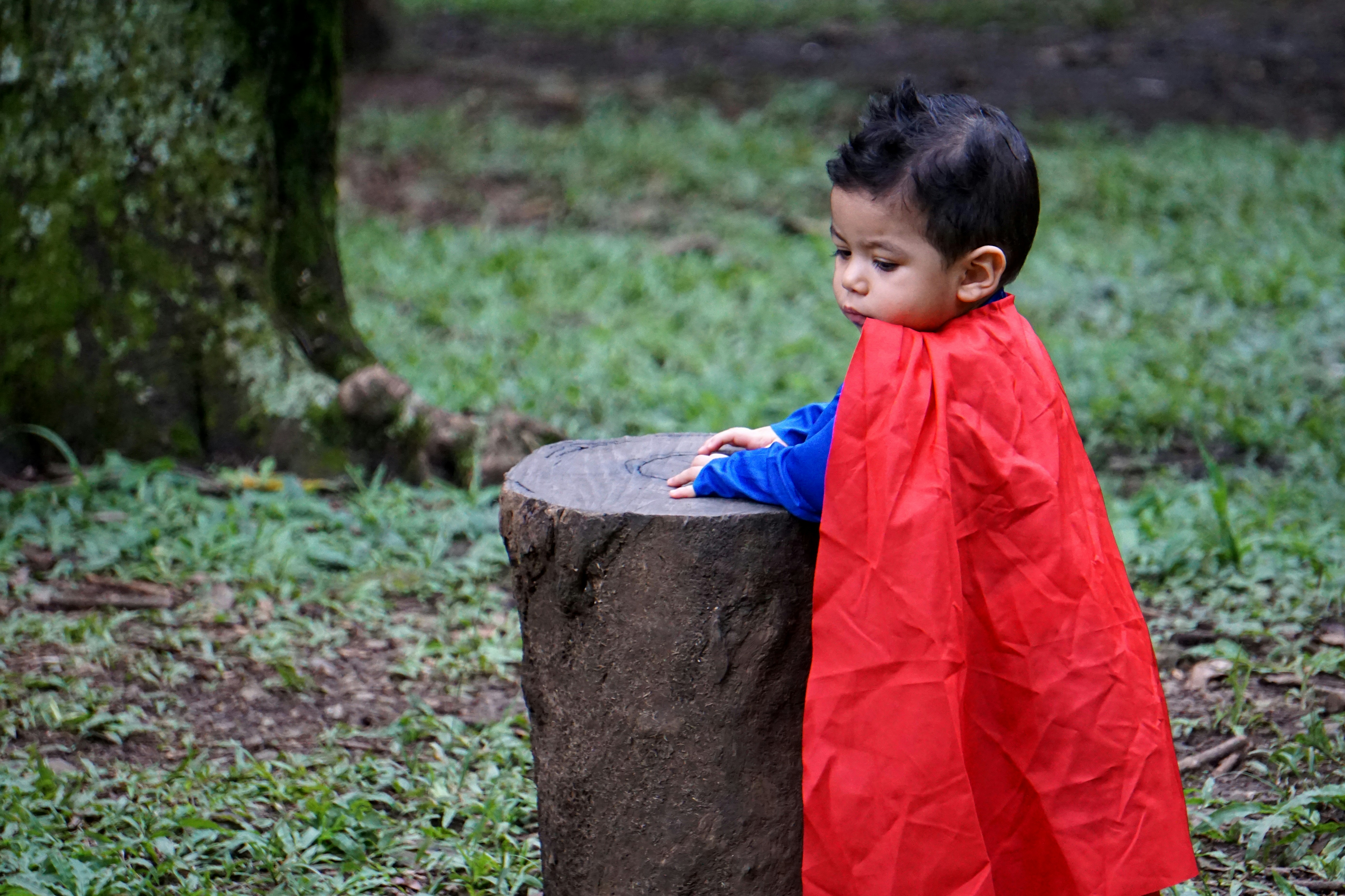 shallow focus photo of boy wearing red cape