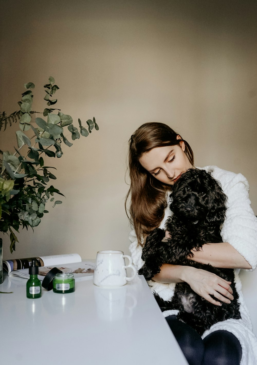 woman carrying black curly coated dog