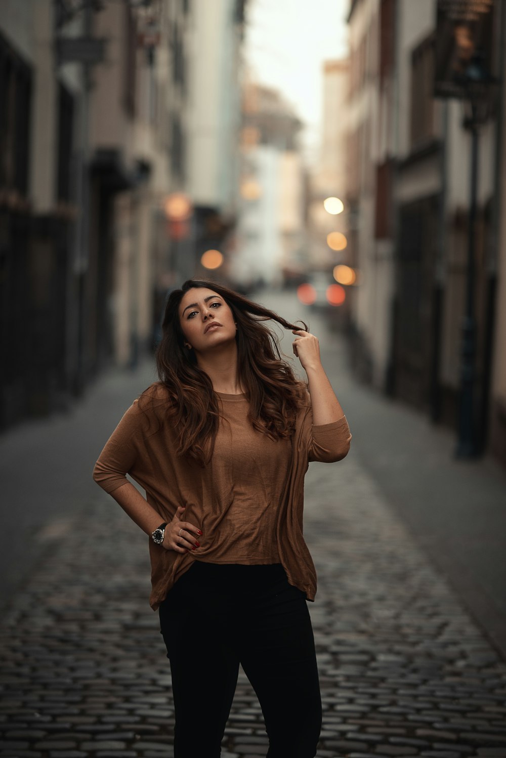 woman standing in the middle of buildings while holding her hair