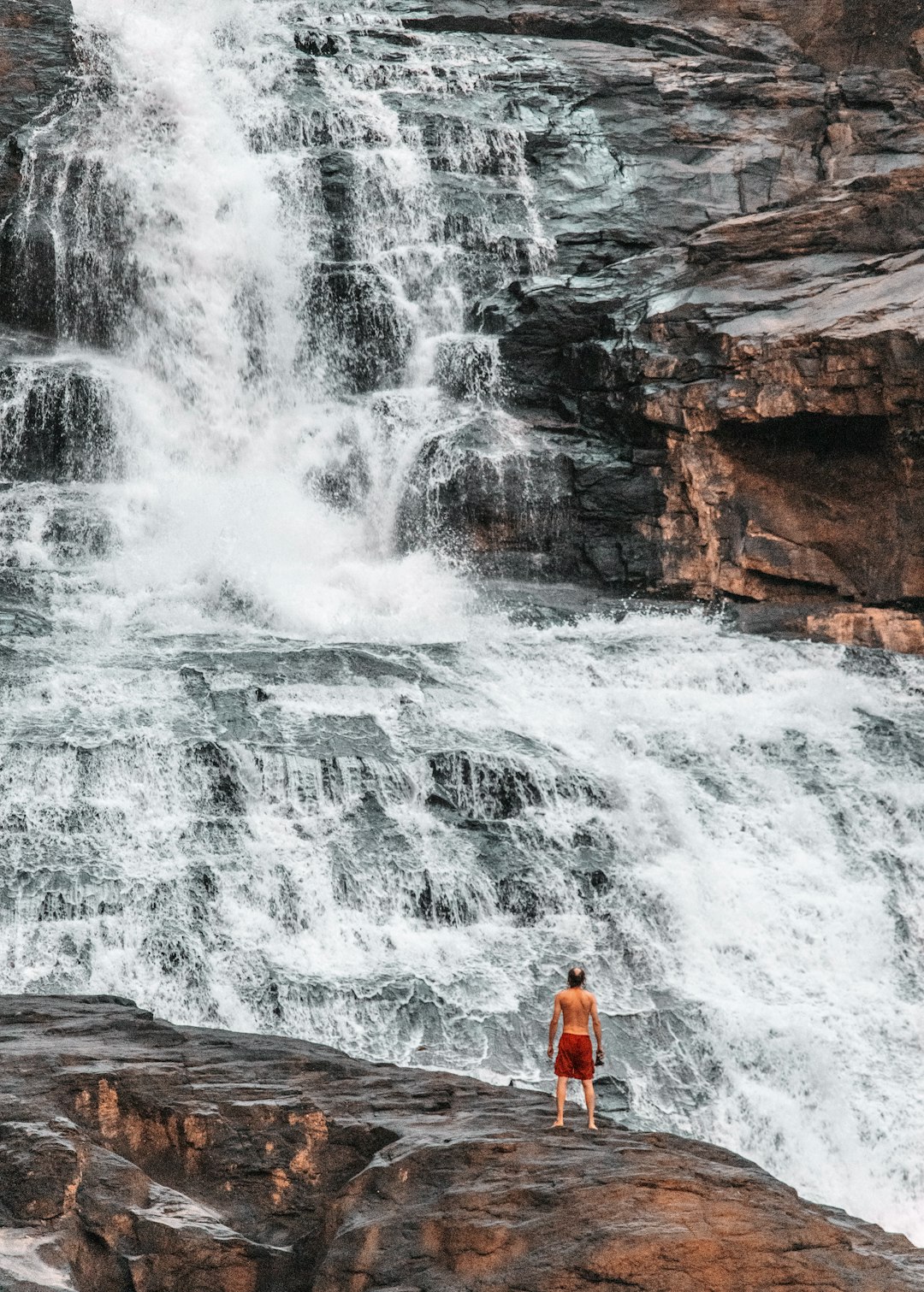 man standing infront of large waterfall