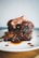 Succulent ribs coated in a rich, glossy barbecue sauce, resting on a white plate. The meat appears tender and well-cooked, with some sauce drizzled around the plate.