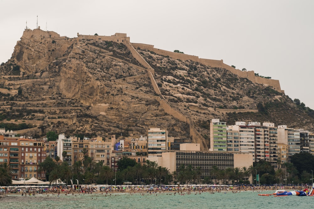 people in beach near buildings and mountain