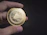 A hand is holding a shiny, gold-colored coin with intricate designs and the word 'Skycoin' inscribed on it. The coin features a cloud emblem in the center with a network-like pattern surrounding it, suggesting a technological or digital theme.