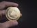A hand is holding a shiny, gold-colored coin with intricate designs and the word 'Skycoin' inscribed on it. The coin features a cloud emblem in the center with a network-like pattern surrounding it, suggesting a technological or digital theme.