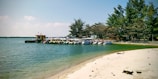 A peaceful beach scene with crystal clear water and colorful boats docked.