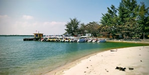 A peaceful beach scene with crystal clear water and colorful boats docked.