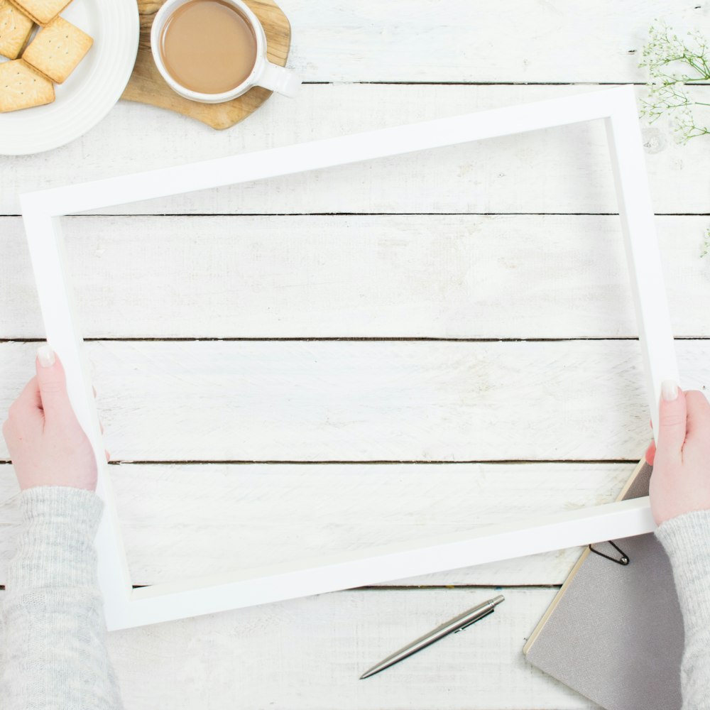 a person holding a picture frame over a table