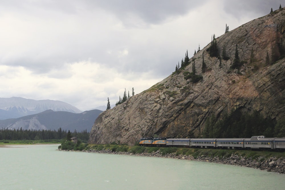 train passant près d’une colline et d’un plan d’eau