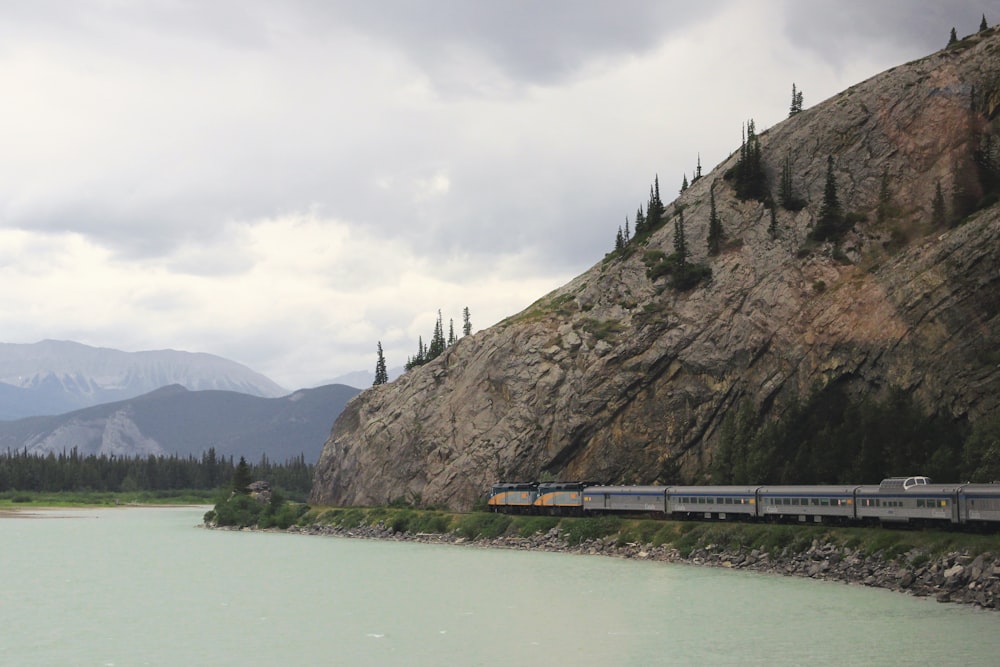 train passing near hill and body of water
