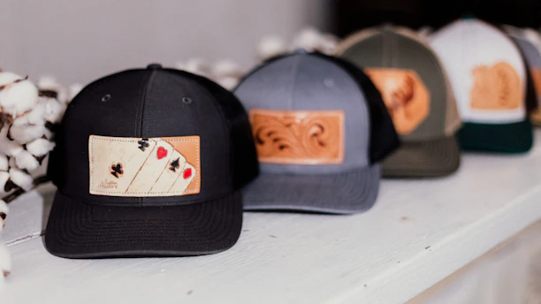 A sleek Cars and Bars branded baseball cap resting on a wooden table with festival wristbands.