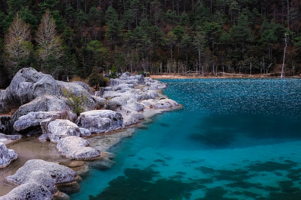 blue body of water beside rock formation