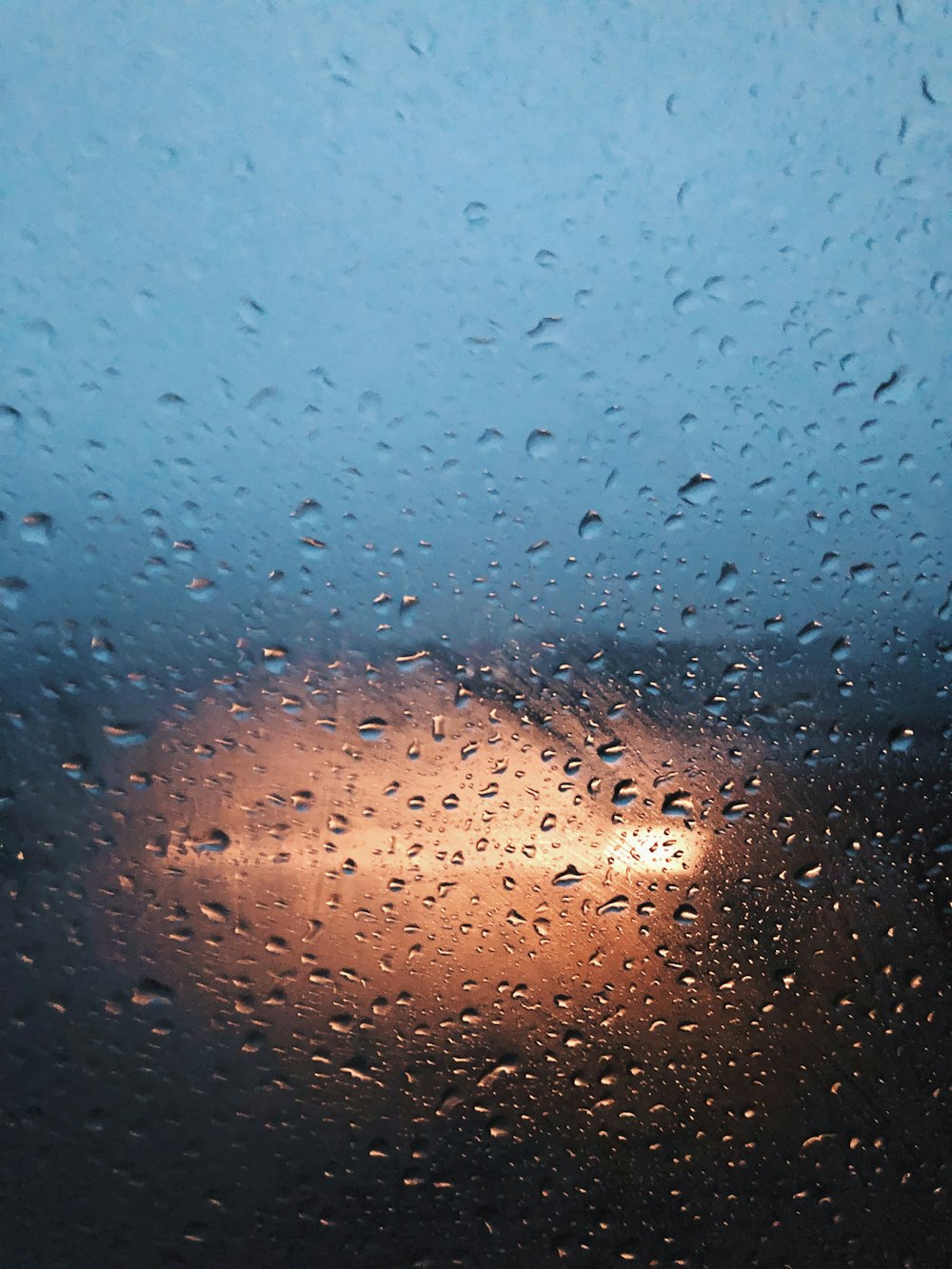 a rain covered window with a street light in the background