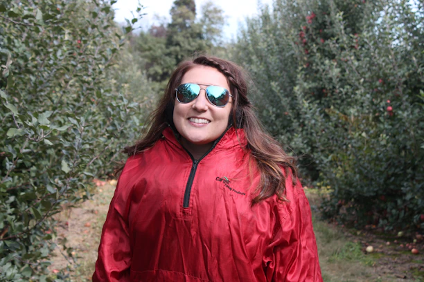 Happy customer wearing a ruby red retro jacket, smiling in a sunlit urban street setting.