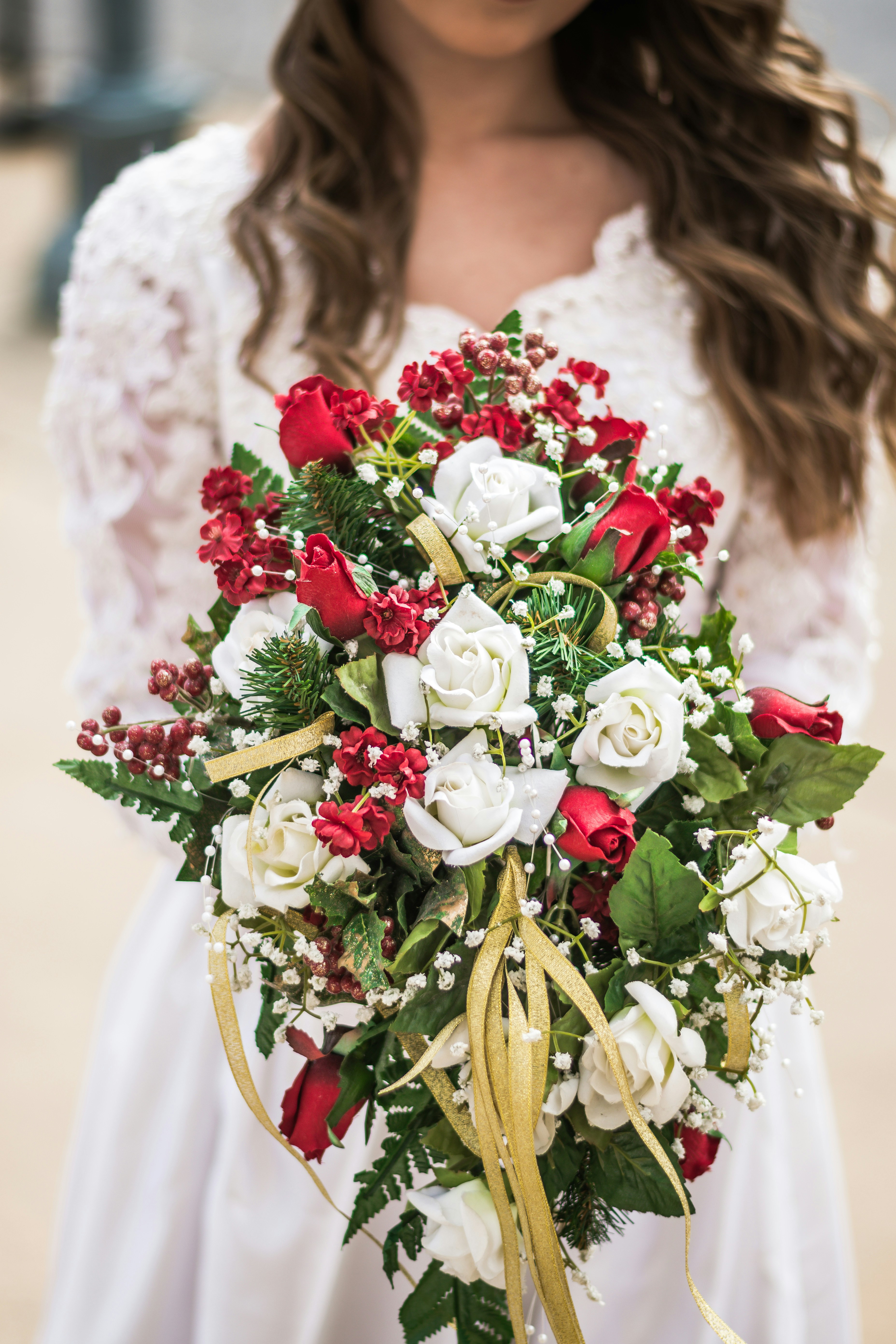 Elegant white wedding bouquet with garden roses and trailing greenery on dark background