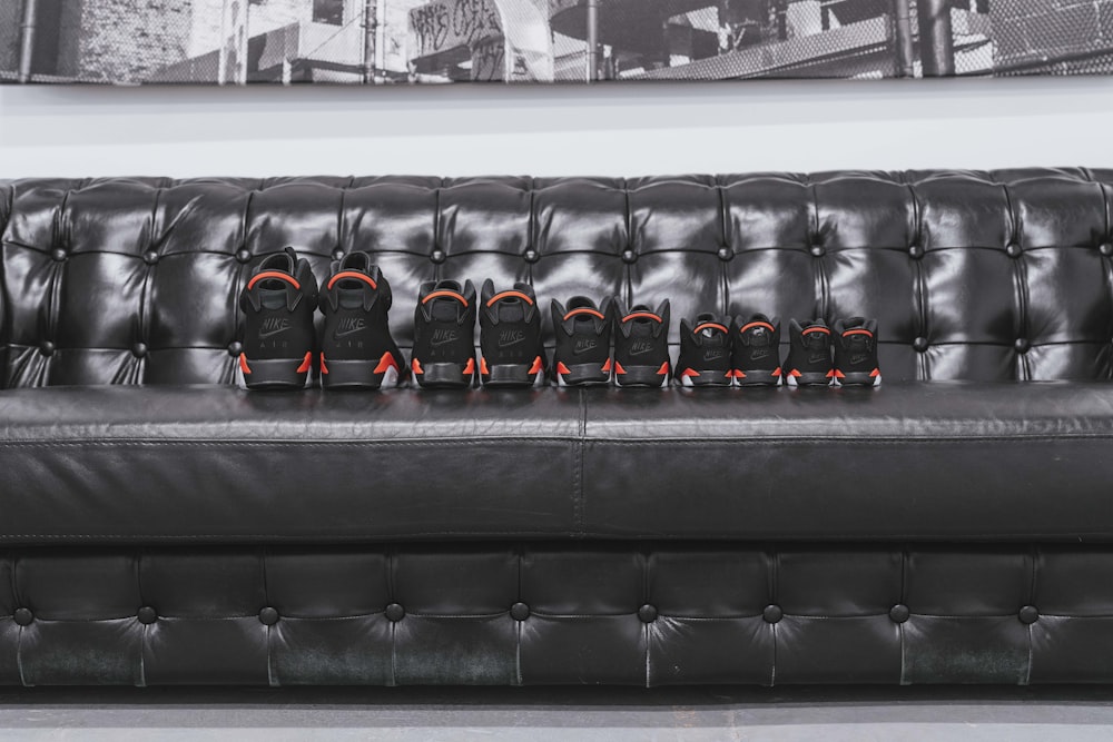 five pairs of assorted-size black shoes on tufted black leather sofa