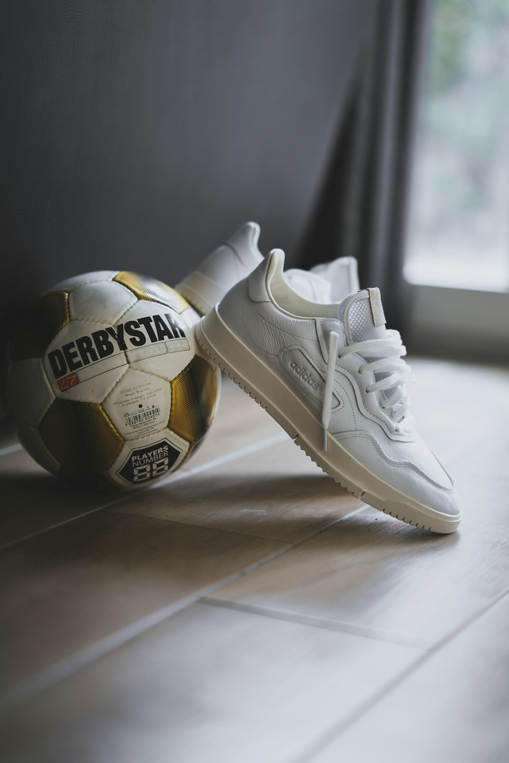 Pair of low-top sneakers beside Derbystar soccer ball photo Free Image on Unsplash
