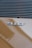 A close-up view of a car badge displaying the text '911T' on a smooth, reflective surface. The badge is metallic and prominently positioned against a light brown or bronze background. Horizontal vents or grille lines are visible above the badge, adding texture.